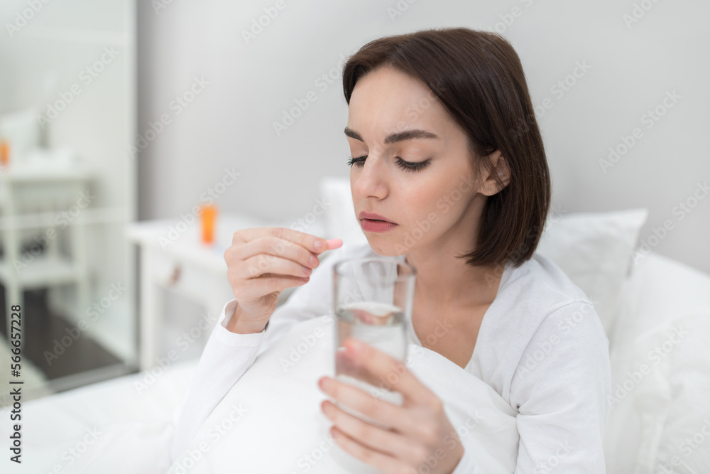 Young woman holding glass of water and pink madicine Young woman holding glass of water and pink madicine