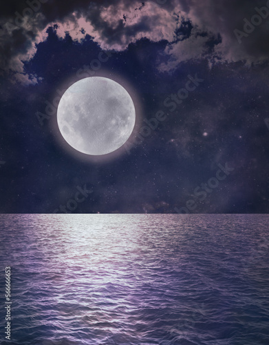 Beautiful Romantic Full Moon Ocean Reflection - dark blue sky with pink tinged clouds and a low full moon over rippling water ideal for astrology or spiritual pagan theme background
