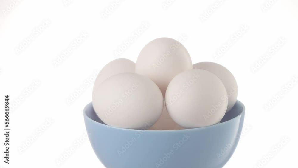 Chicken eggs in a blue bowl moving on a white background. protein foods. High quality 4k footage Chicken eggs in a blue bowl moving on a white background. protein foods. High quality 4k footage