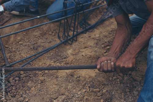 Worker ties wire metal steel to building structure at construction site. Man hand holding material Metal Steel reinforced rod for concrete