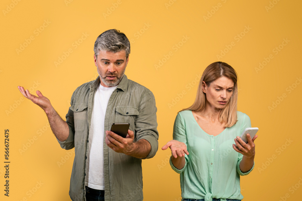 Internet connection problem. Confused middle aged caucasian couple looking at their phones and shrugging shoulders