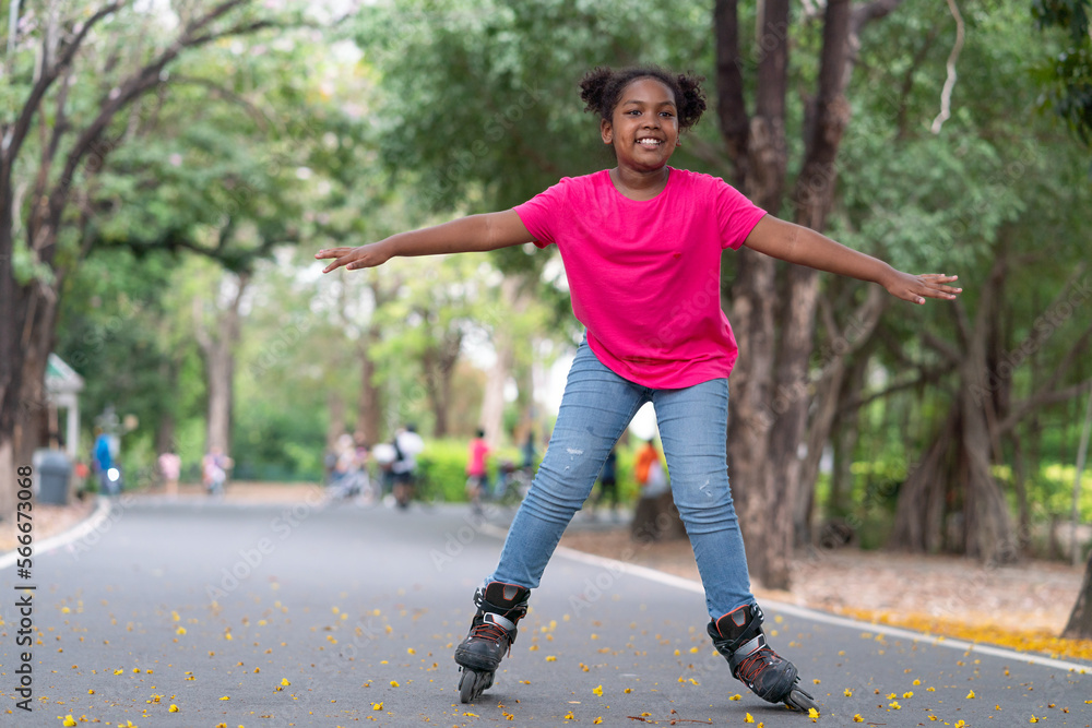 Happy African American girl playing roller skate on road in park.Sport outdoor for kid. Happy African American girl playing roller skate on road in park.Sport outdoor for kid.