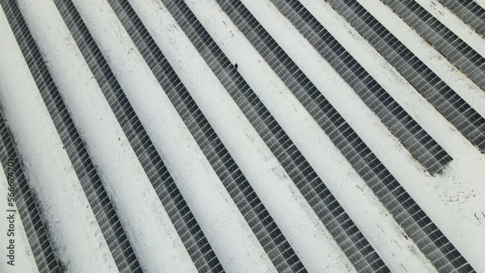 Aerial view of electrical power plant with solar panels covered with snow melting down in winter end for producing clean energy. Concept of low effectivity of renewable electricity in northern region Aerial view of electrical power plant with solar panels covered with snow melting down in winter end for producing clean energy. Concept of low effectivity of renewable electricity in northern region