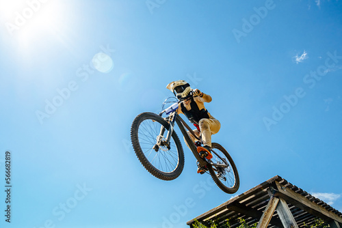 girl rider drops downhill in background blue sky