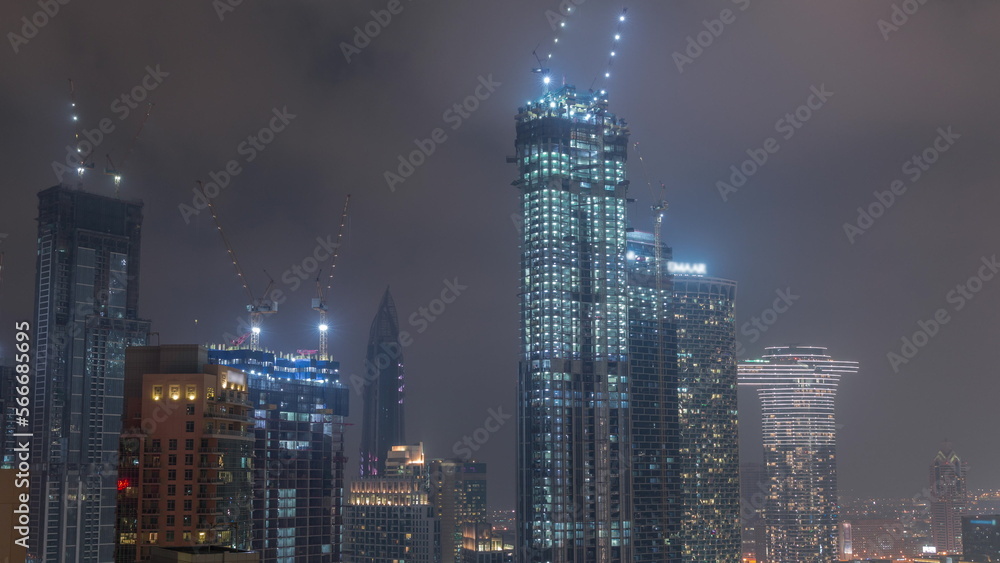 Obraz premium Cranes working on modern constraction site works of new skyscrapers night