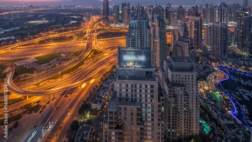 Dubai marina and JLT skyscrapers along Sheikh Zayed Road aerial night to day .