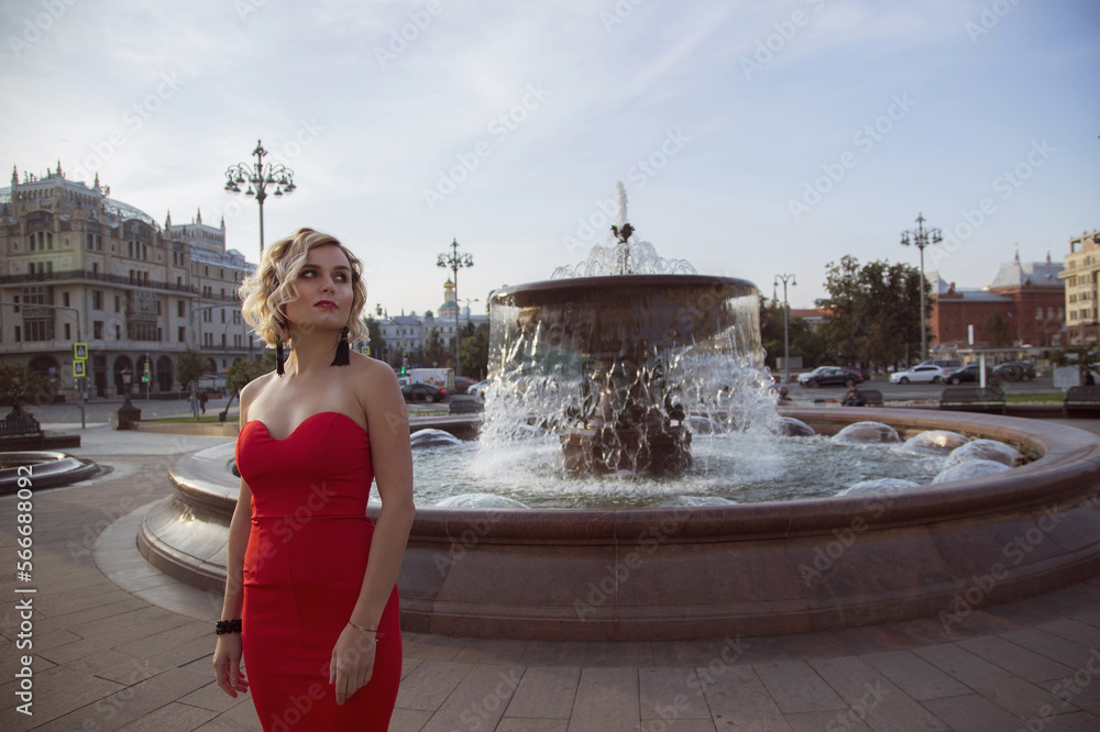 Portraite woman in a sexy red dress walks in the center of Moscow.