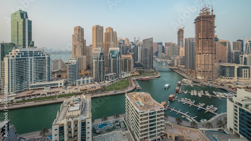 Panorama showing Dubai Marina with several boat and yachts parked in harbor and skyscrapers around canal aerial . © neiezhmakov