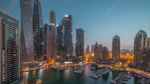 Dubai marina tallest skyscrapers and yachts in harbor aerial night to day .