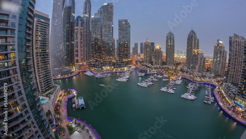 Dubai marina tallest skyscrapers and yachts in harbor aerial day to night .