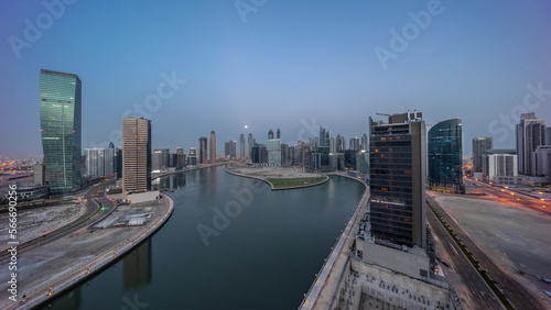 Cityscape of skyscrapers in Dubai Business Bay with water canal aerial night to day