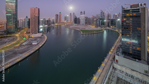 Cityscape of skyscrapers in Dubai Business Bay with water canal aerial night to day