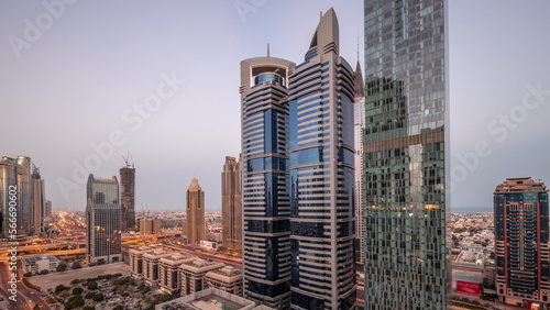 Aerial view of Dubai International Financial District with many skyscrapers night to day .