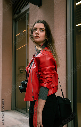 Stylish girl wearing red leather jacket. Her hair is flying.