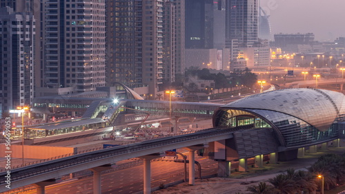 Futuristic building of Dubai metro station and luxury skyscrapers behind in Dubai Marina aerial night to day