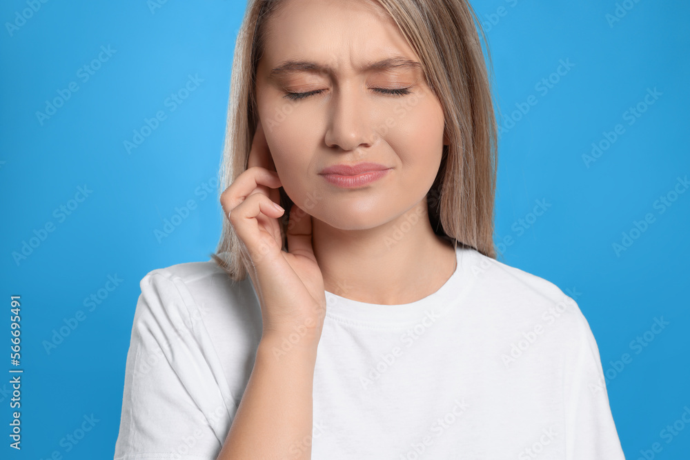 Young woman suffering from ear pain on light blue background Young woman suffering from ear pain on light blue background