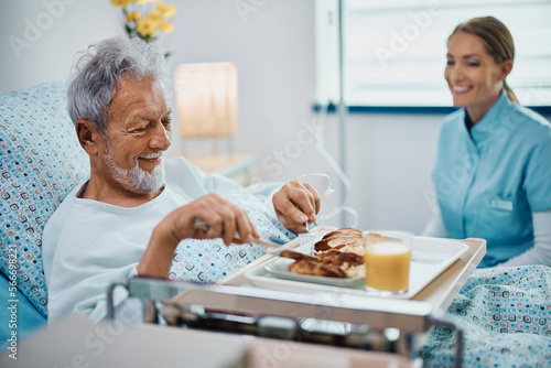 Fotografia Happy senior patient having meal while recovering in hospital.