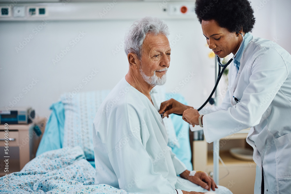 Black cardiologist using stethoscope while visiting her senior patient at hospital ward. Black cardiologist using stethoscope while visiting her senior patient at hospital ward.