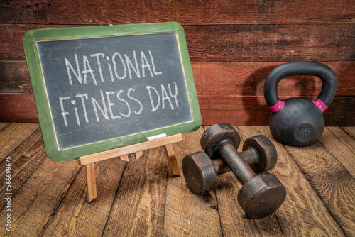 Fototapeta Naklejka Na Ścianę i Meble -  National Fitness Day is celebrated on the first Saturday of May in US, white chalk text on blackboard with dumbbells and kettlebell