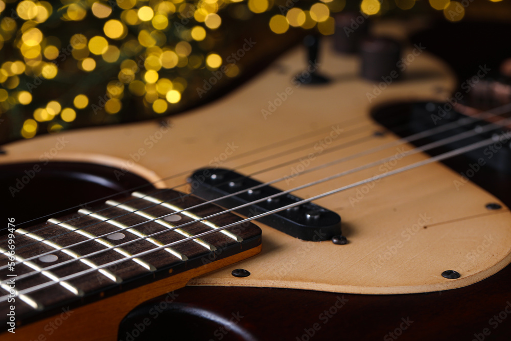 Fototapeta premium Closeup view of guitar against blurred lights