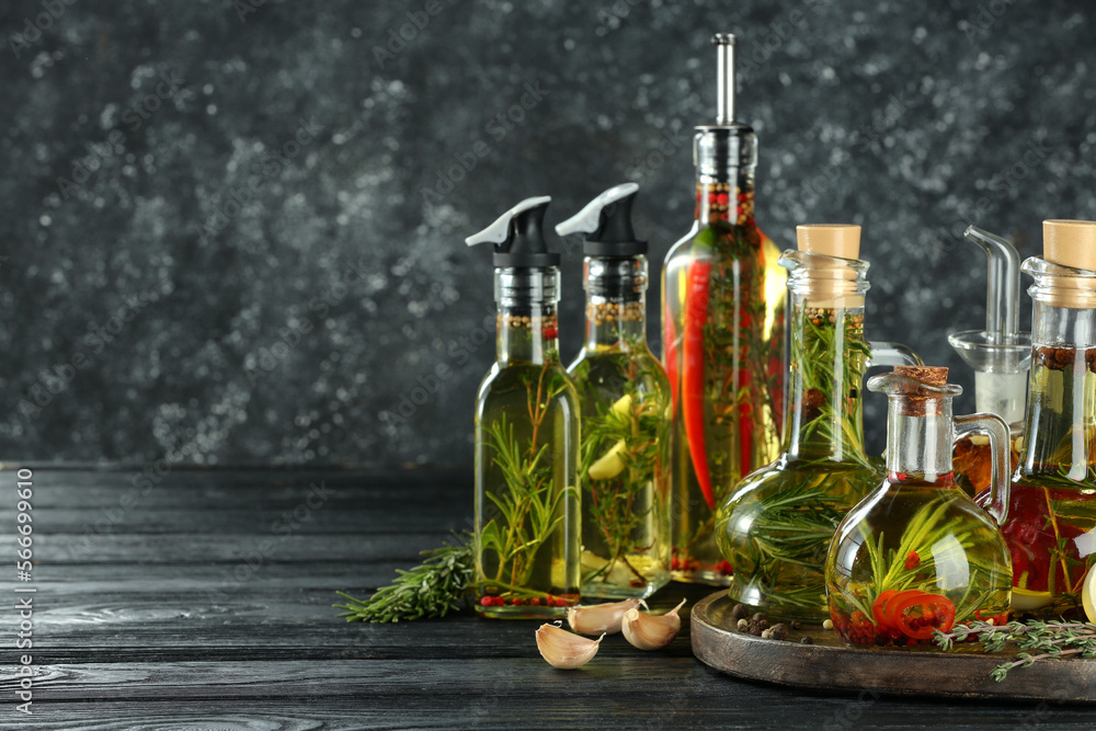 Cooking oil with different spices and herbs in bottles on grey wooden table. Space for text Cooking oil with different spices and herbs in bottles on grey wooden table. Space for text