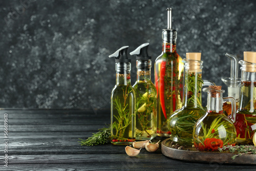 Fototapeta Naklejka Na Ścianę i Meble -  Cooking oil with different spices and herbs in bottles on grey wooden table. Space for text