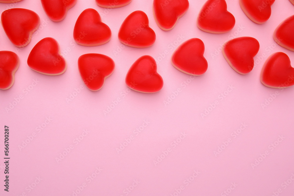 Delicious heart shaped jelly candies on pink background, flat lay. Space for text