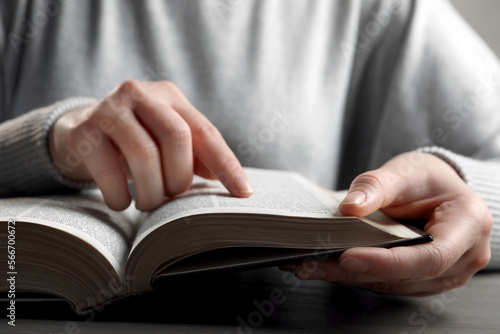 Woman reading Bible at wooden table, closeup