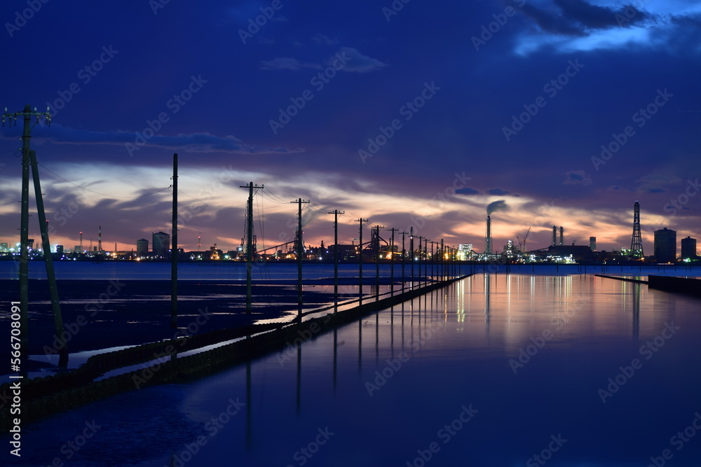 夕暮れ時の江川海岸の海上電柱と対岸に望む工場群