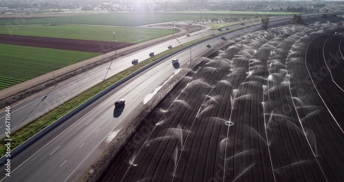 Highway and Irrigation Agriculture Field in California, United States. Sprinkler system waters rows of lettuce crops on farmland in the Salinas Valley