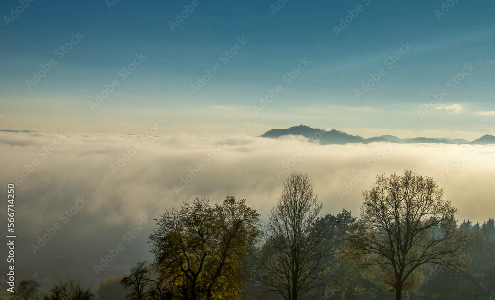 Fototapeta premium Heavy fog and mist surrounds forested mountain peaks 