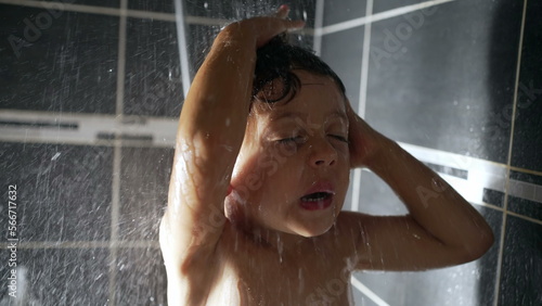 One happy cute little boy in shower. Washing child closeup face. Water falling in kid head in slow motion