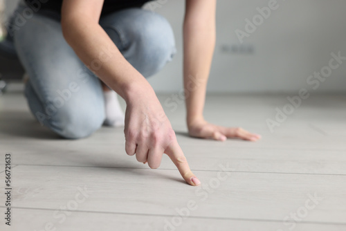 Woman housewife pointing finger at dirt on floor with laminate closeup