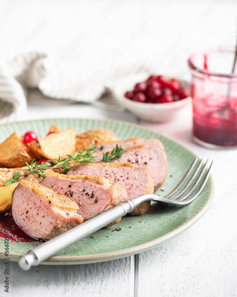Duck breast with potatoes and berry sauce on white background, selective focus Duck breast with potatoes and berry sauce on white background, selective focus