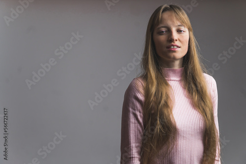 Portrait of young long-haired woman with condifent look standing in front of gray studio background. High quality photo photo