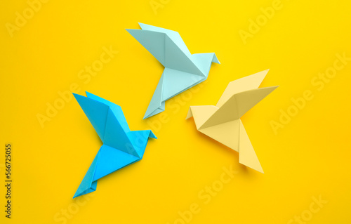 Origami art. Colorful handmade paper birds on yellow background  flat lay