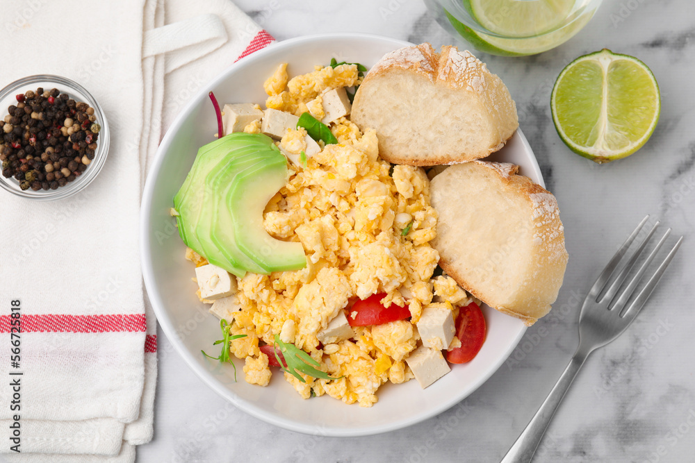 Bowl with delicious scrambled eggs, tofu, avocado and slices of baguette on white marble table, flat lay Bowl with delicious scrambled eggs, tofu, avocado and slices of baguette on white marble table, flat lay