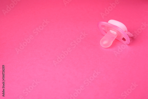 One baby pacifier on pink background. Space for text