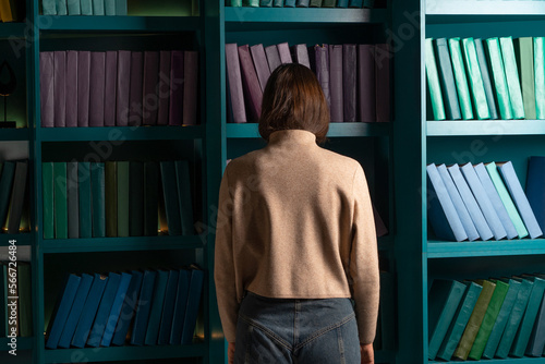 Depression and chronic fatigue. Cognitive overload from an overabundance of news and information noise, concept. An apathetic woman stands with her face buried in bookshelves.