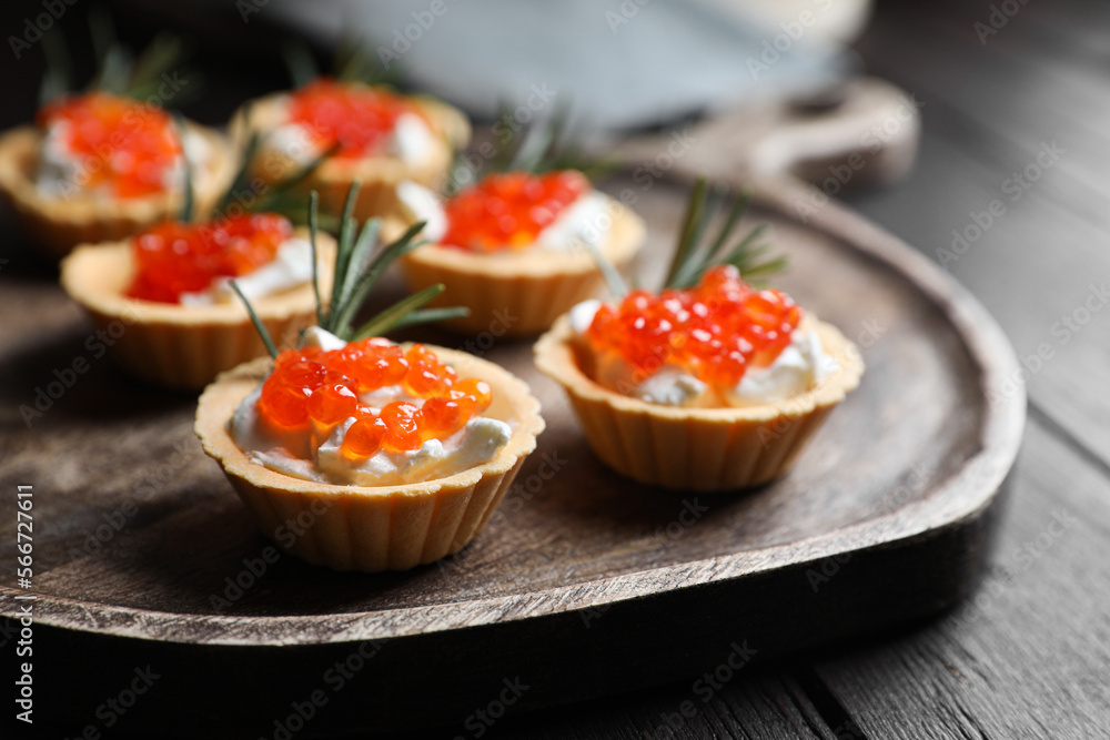 Delicious tartlets with red caviar and cream cheese served on wooden table, closeup Delicious tartlets with red caviar and cream cheese served on wooden table, closeup