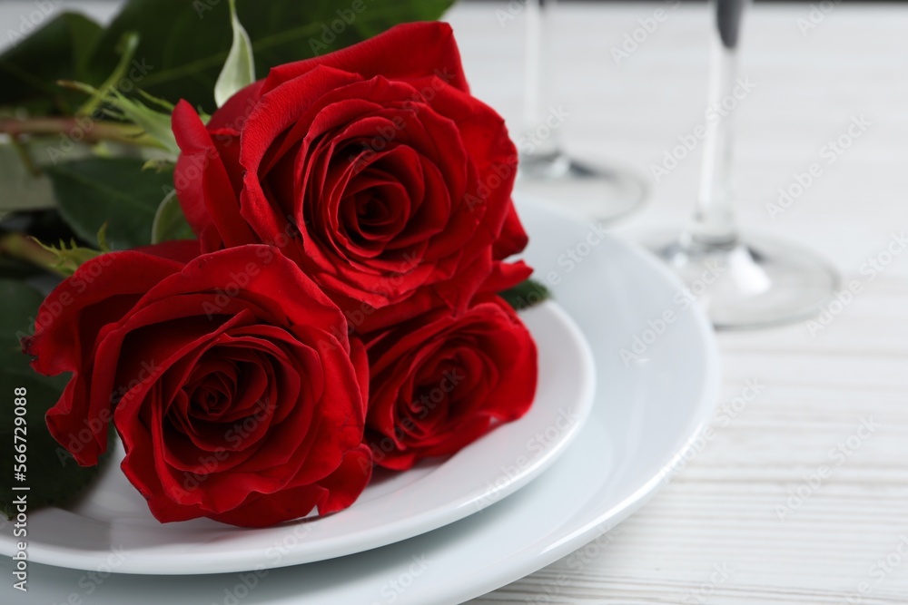 Beautiful place setting with dishware and roses for romantic dinner on white wooden table, closeup Beautiful place setting with dishware and roses for romantic dinner on white wooden table, closeup