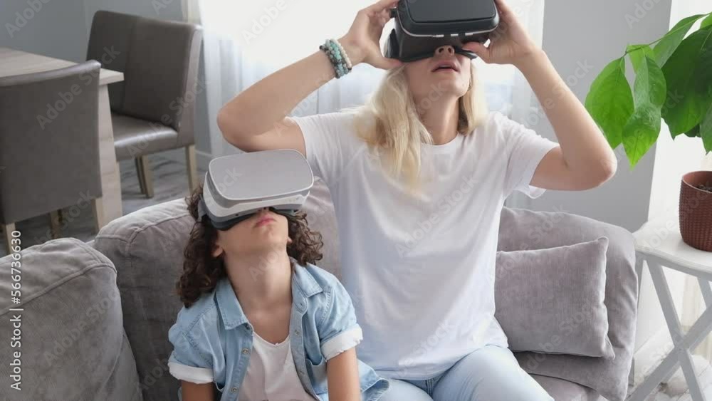 Mother and son wearing virtual reality headset vr glasses in living room at home having fun interacting with virtual reality playing games Mother and son wearing virtual reality headset vr glasses in living room at home having fun interacting with virtual reality playing games
