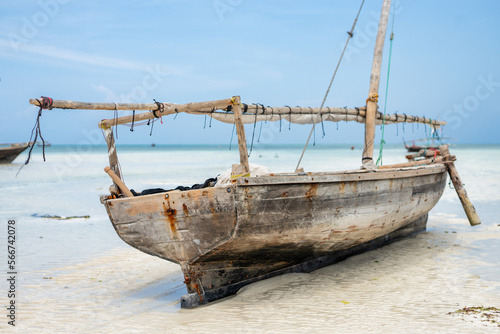 Wooden boat anchored on the African shore Zanzibar in clear ocean water