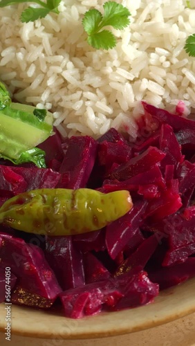 Close-up view of beetroot curry with sona masoori rice and stir-fried lettuce. Table spin. Vertical video. photo