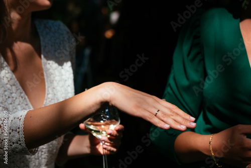 A newlywed bride shows her wedding ring to her guests at the cocktail party.
