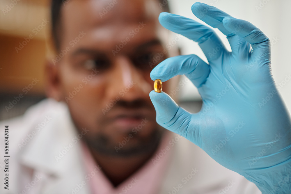 Medical scientist holding pill with fish oil, selective focus Medical scientist holding pill with fish oil, selective focus