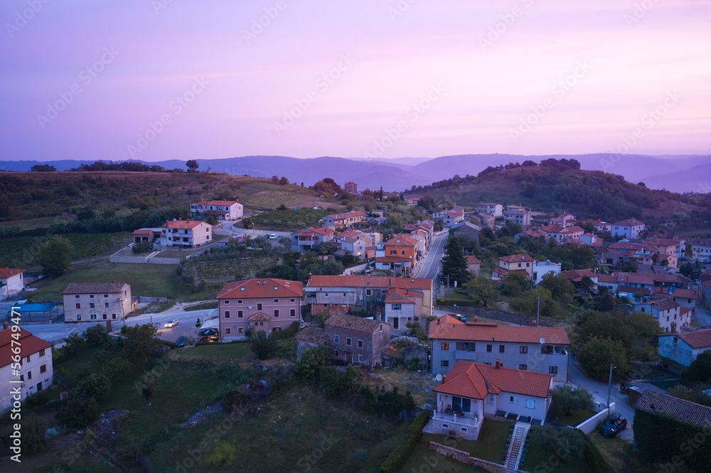 A delightful early morning in a Croatian village in a hilly area. Houses with tiled roofs in the pink of the rising sun. Shot from a drone.
