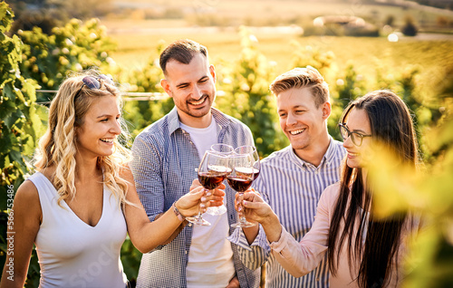 Young friends having fun outdoors - Happy people enjoying harvest time together at farmhouse winery countryside - Tasting red wine at vineyard - Focus on the girl's face with glasses © napeter