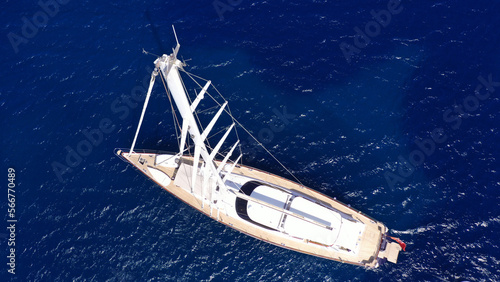 Aerial drone top down photo of beautiful sail boat with wooden deck anchored in deep blue Mediterranean sea