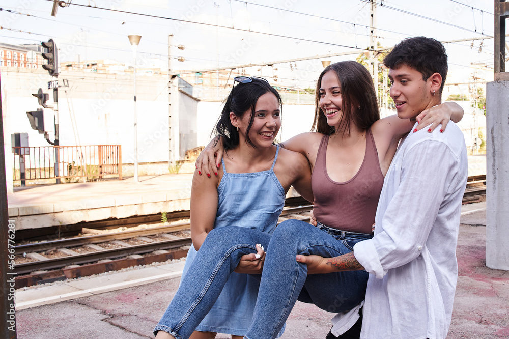 three young friends having fun. group of millennials carrying a young caucasian girl in their arms.